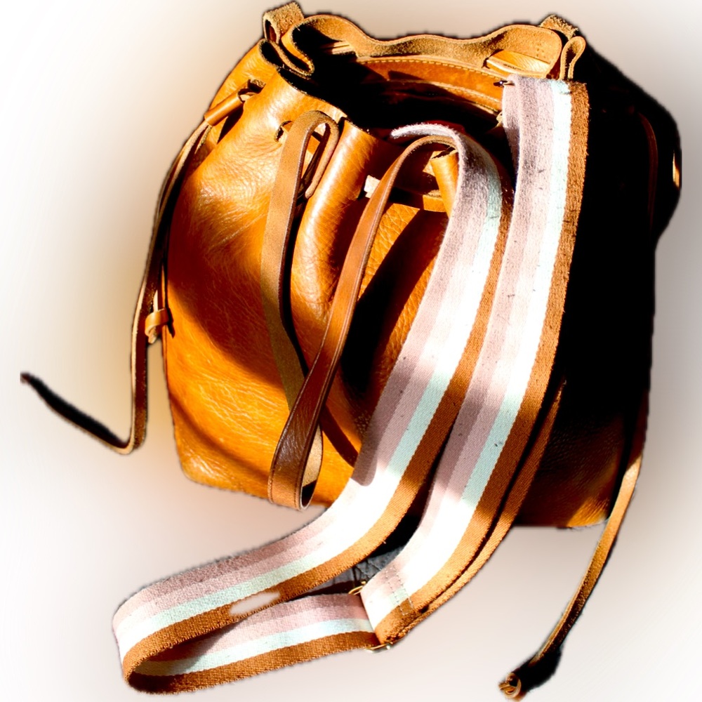Madewell leather drawstring bucket bag with striped crossbody strap.